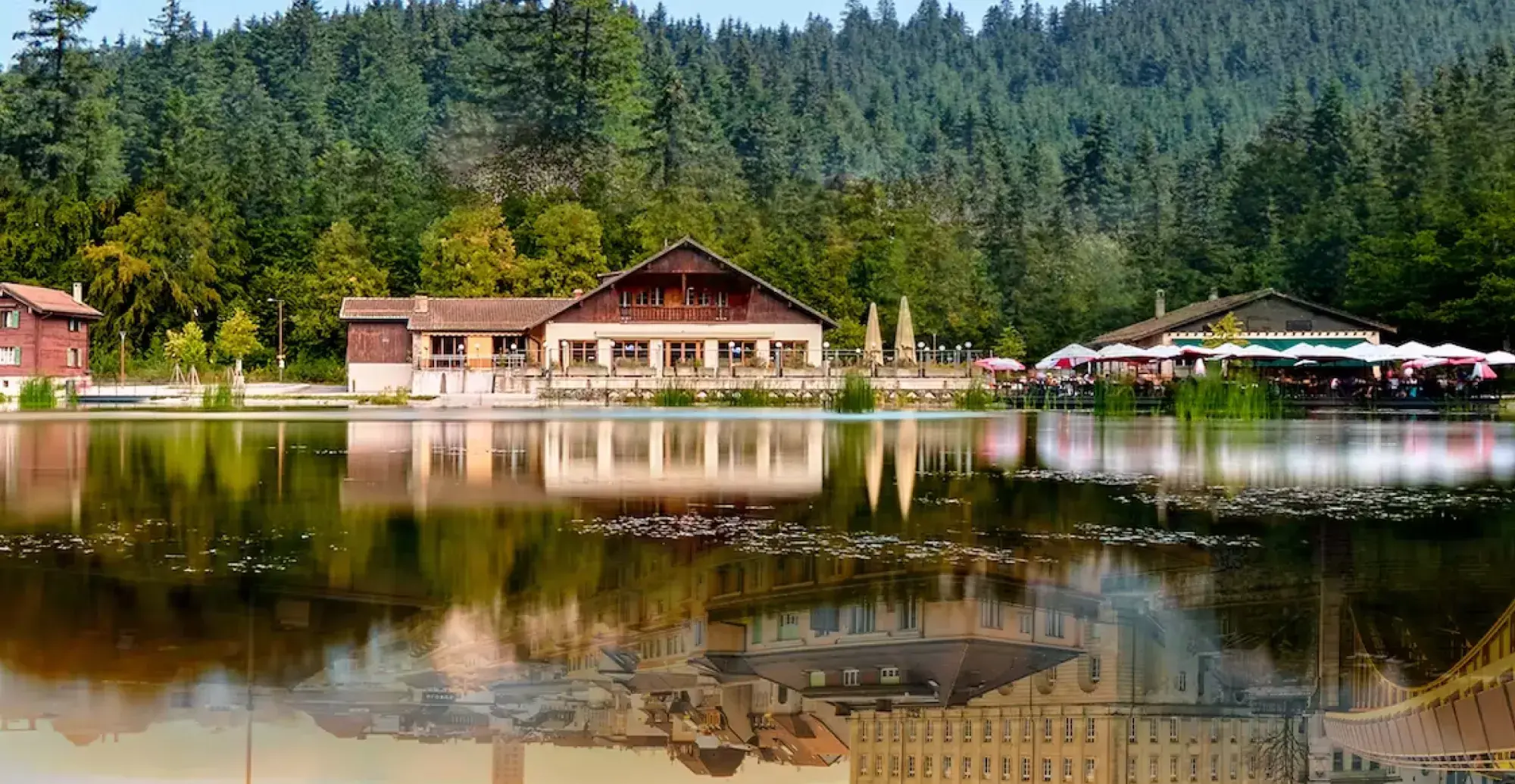 Reflection of houses on a lake surrounded by forest - Lausanne Tourisme project Marvelous Digital